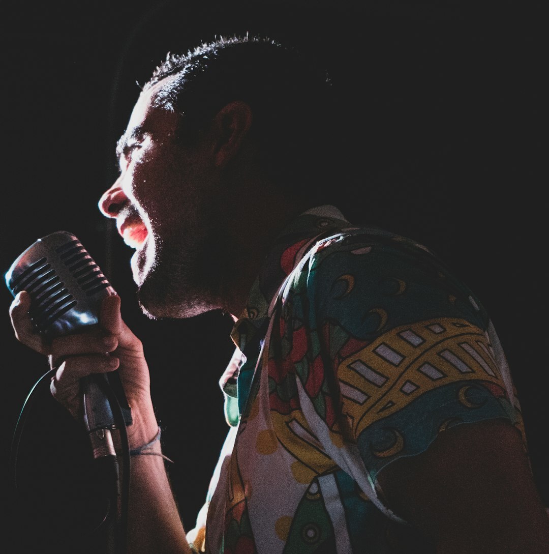 Musician singing passionately on stage under a spotlight